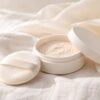 白いリネンの上に置かれた天然シルクの布と、ふたを開けたパウダーケース(イメージ)
