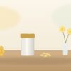 サプリメントの容器とカプセル、ミツバチの巣と花を並べたイメージ(当サイトで作成)
